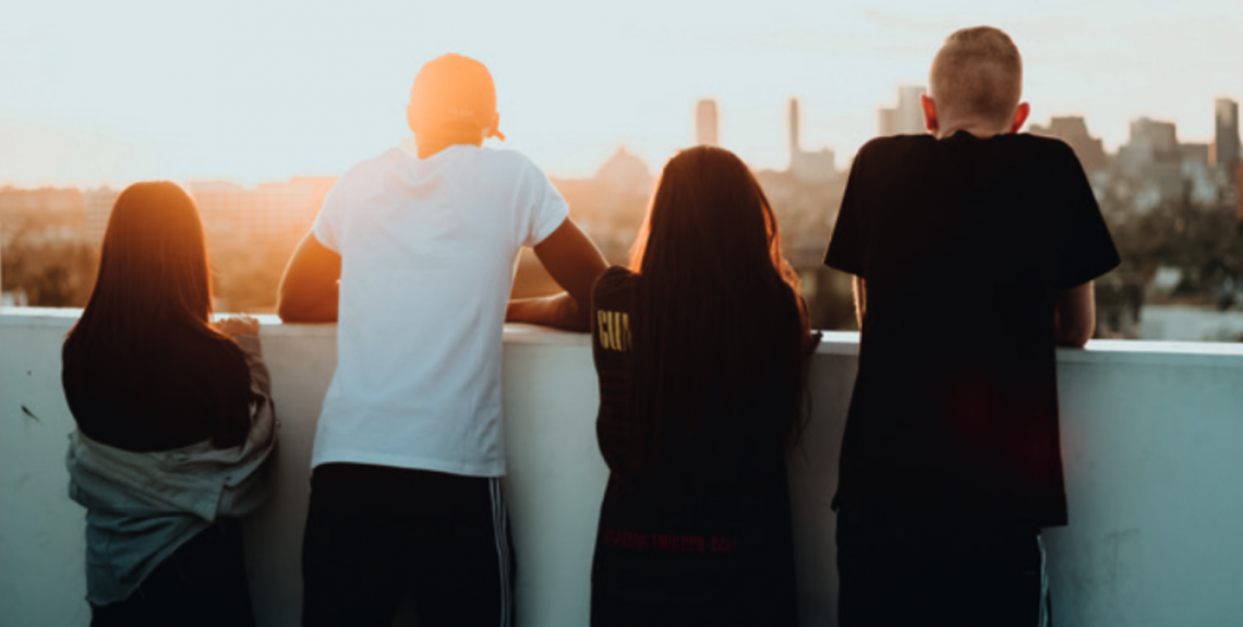 Four teenagers looking at a city landscape.